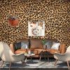 A living room wall covered in leopard print self-adhesive wallpaper with a brown leather sofa and decorative pillows.