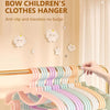 A close-up of a pink and purple adjustable clothes hanger rack with cute cloud decorations against a light wall.