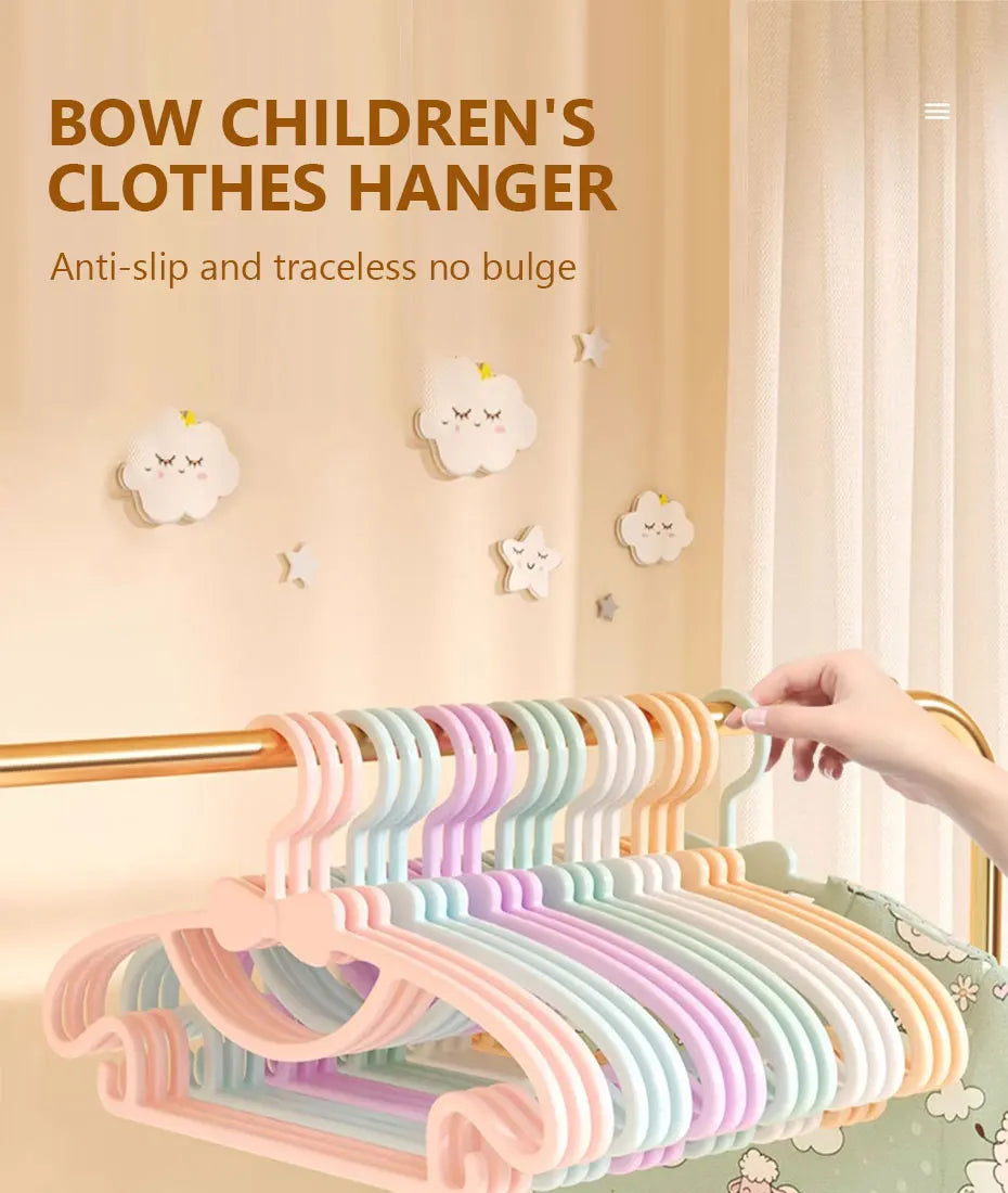 A close-up of a pink and purple adjustable clothes hanger rack with cute cloud decorations against a light wall.