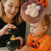 A young child is interacting with a black foam cat paw soap dispenser while a woman observes.