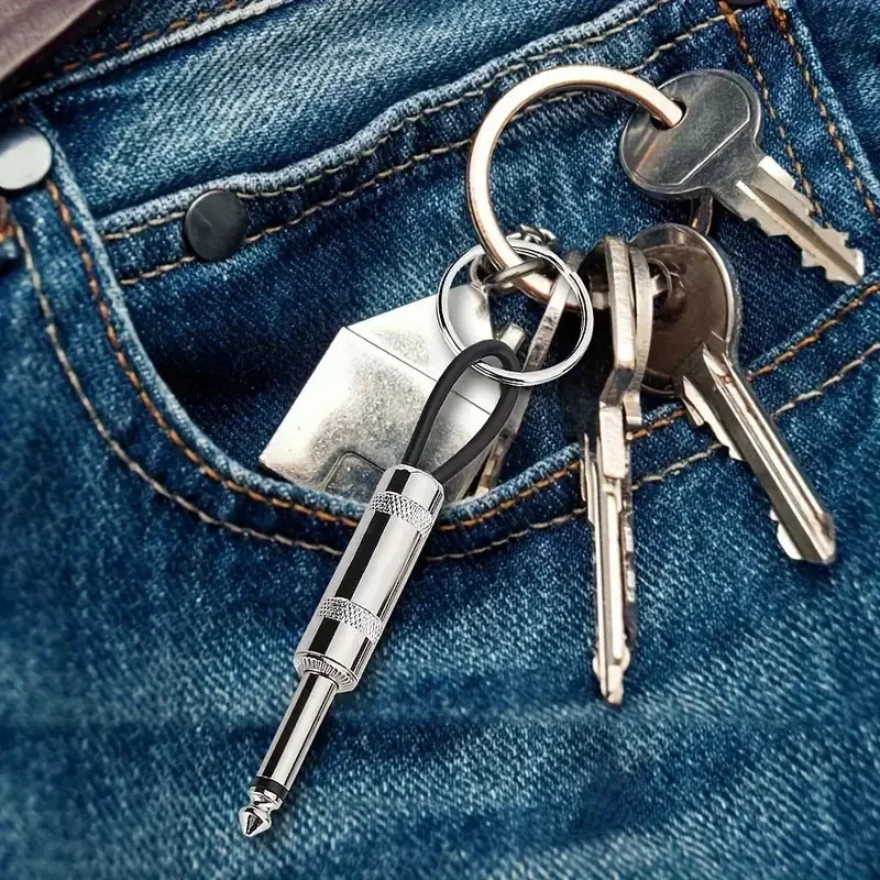 A set of vintage-style wall keys and a silver pen attached to a keyring, resting in a blue denim pocket.