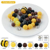 A collection of 45 round silicone beads in various colors including yellow, black, and brown, displayed on a white plate.