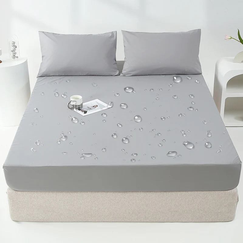 Una funda ajustada impermeable gris para colchón se muestra en una cama, con gotas de agua visibles en la superficie.