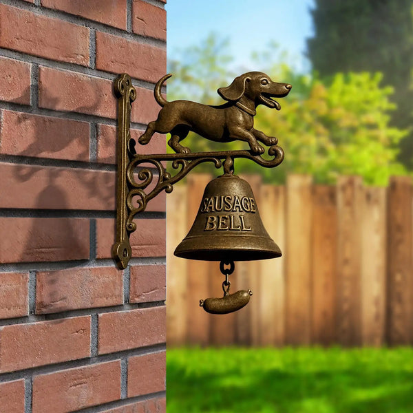 A vintage bronze dachshund doorbell with a hand-crank mechanism mounted on a brick wall.