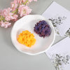 A white ceramic dish holds purple and yellow silicone floral molds for crafting.