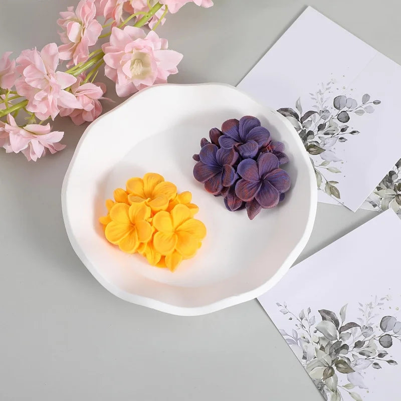 A white ceramic dish holds purple and yellow silicone floral molds for crafting.