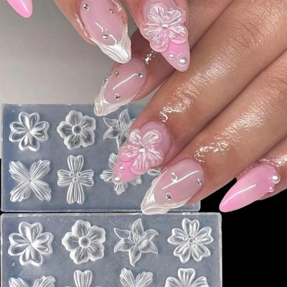 A hand displays pink and white floral nail art created using silicone molds on fingernails.