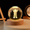 Laser engraved crystal ball night light with a small astronaut figure on a wooden base