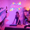 A person is interacting with a neon sign display in a dimly lit room, featuring bright pink and purple light.
