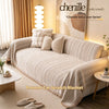 A beige sofa cover blanket with a fishbone pattern is draped over a light-colored sofa in a bright living room setting.