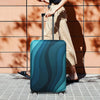 A teal and dark blue stretchable suitcase protector cover is shown being pulled by a person outdoors.