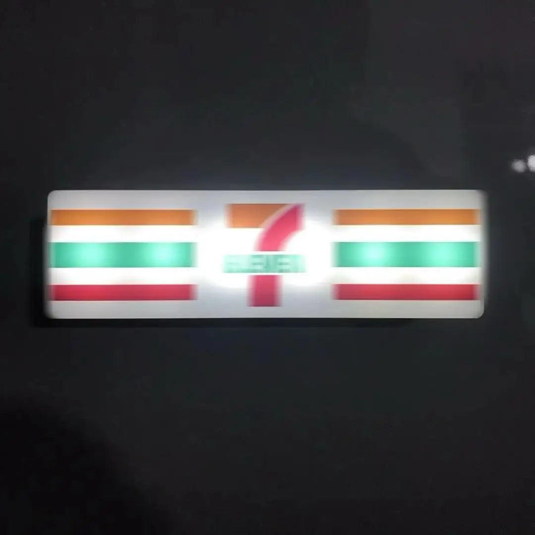 A rectangular fridge magnet featuring the flag of a country with horizontal stripes and a stylized red number 7.