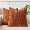 A square, rust-colored handwoven chenille texture cushion cover resting on a light sofa.