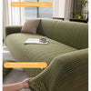 A close-up of a green quilted sofa cover being handled, showing its texture and fit on the furniture.