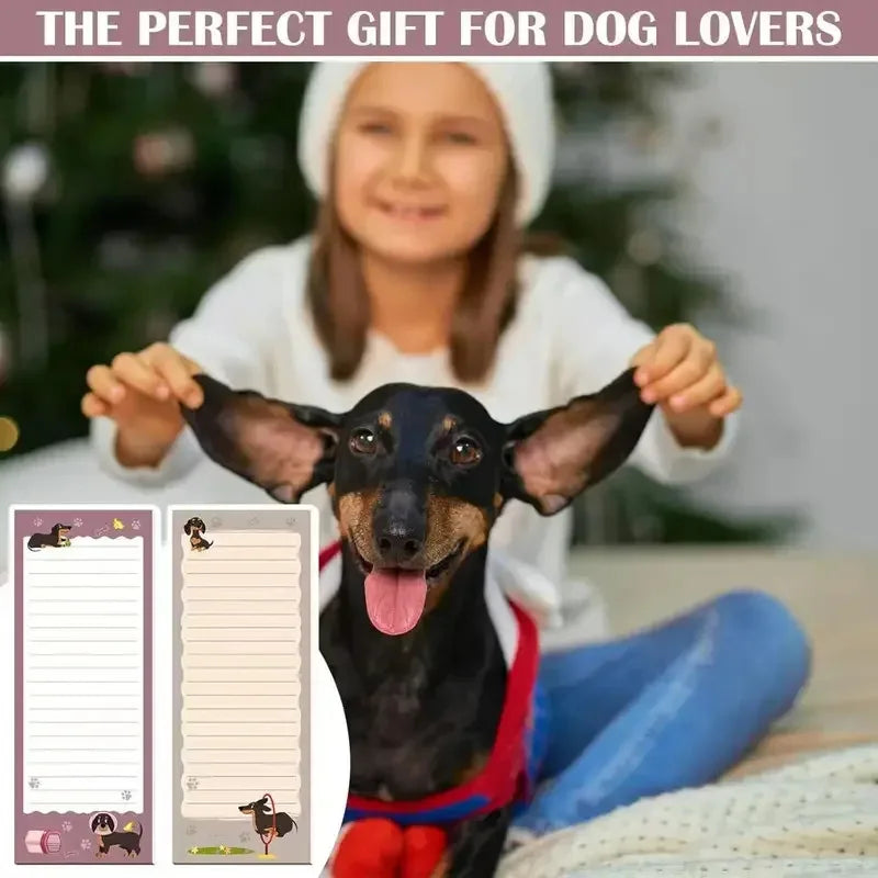 A young girl holds a black dachshund puppy with large ears in front of a Christmas tree.