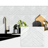 White marble herringbone peel-and-stick wall tiles displayed on a modern kitchen backsplash.