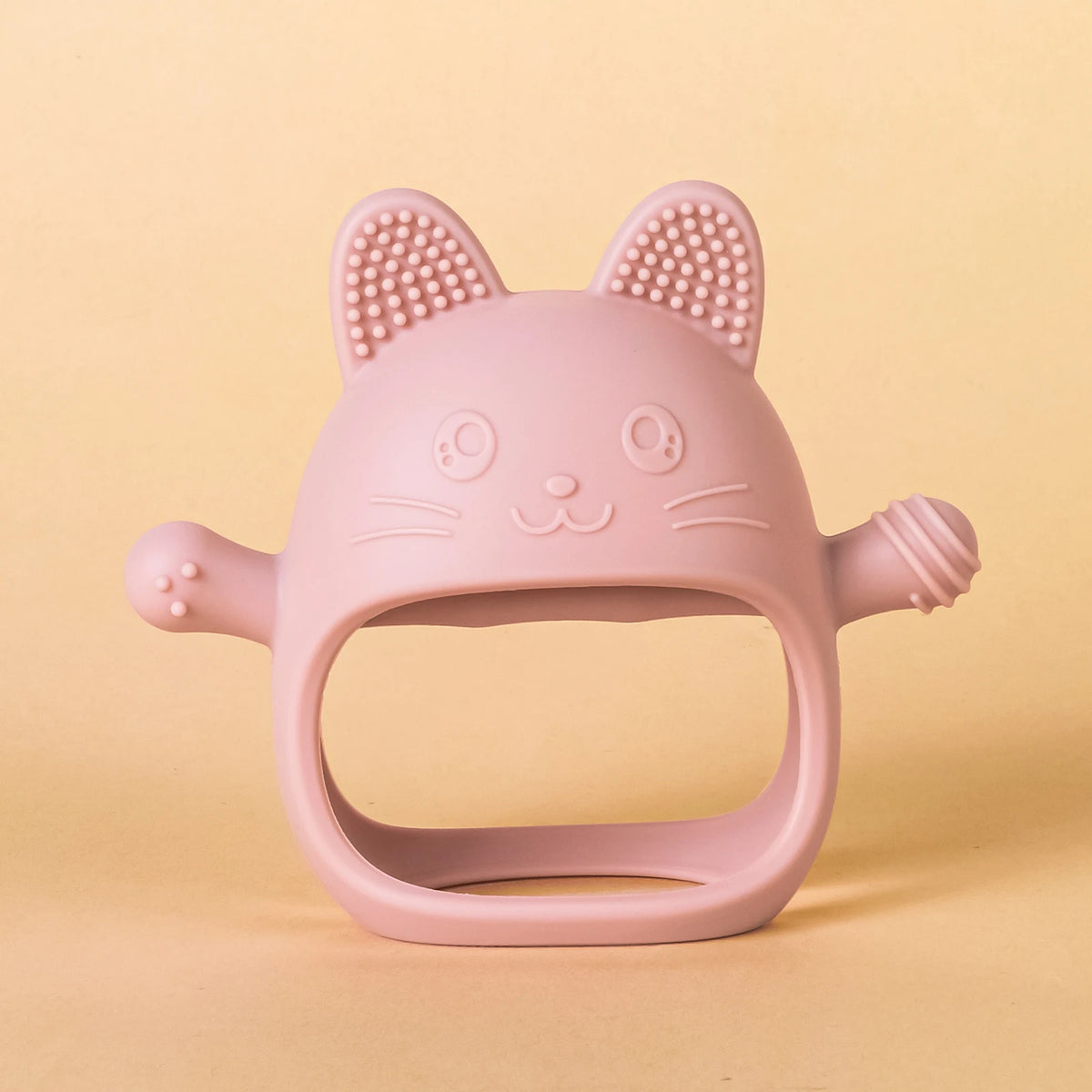 A pink silicone cat teether with pointed ears and whiskers is shown against a light background.