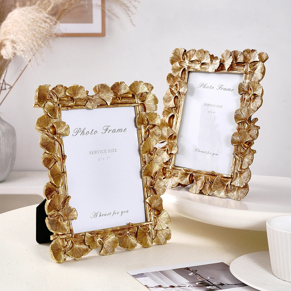 An elegant golden ginkgo leaf resin photo frame displayed on a white surface.