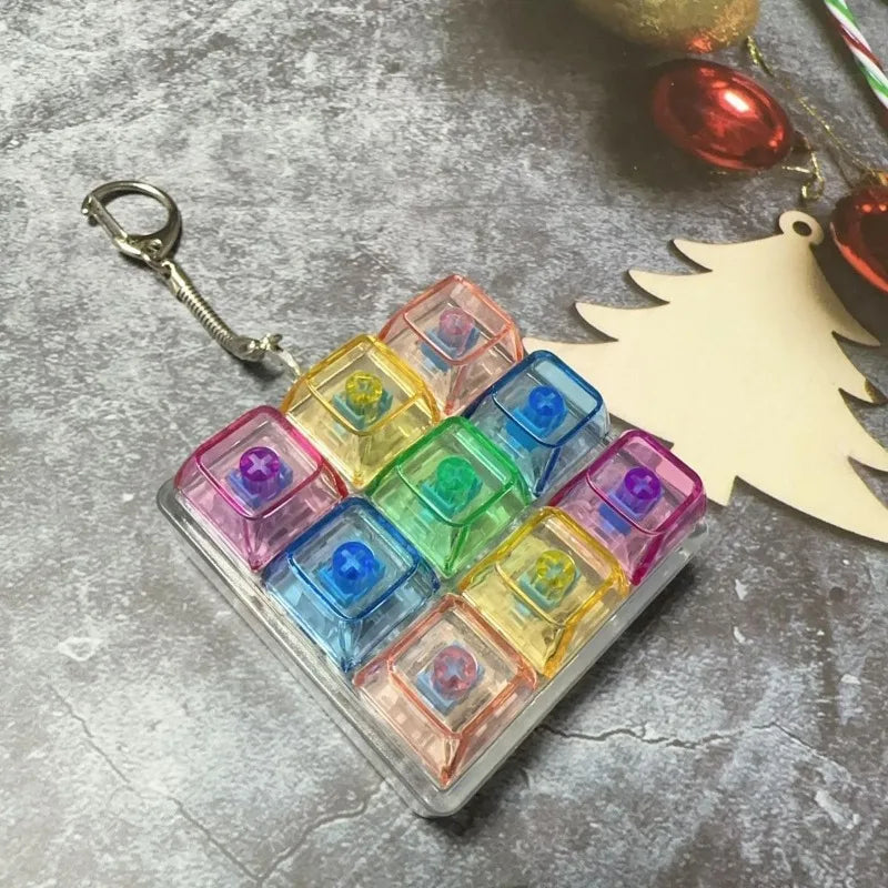 A clear plastic case filled with colorful tactile clicking keyboard fidget toys rests on a gray surface next to a gold orname