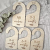 A set of seven wooden baby closet divider hangers marked with age ranges from newborn to 9-12 months