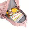 A pink backpack is open, showing a yellow notebook and a gold-colored metal object inside.