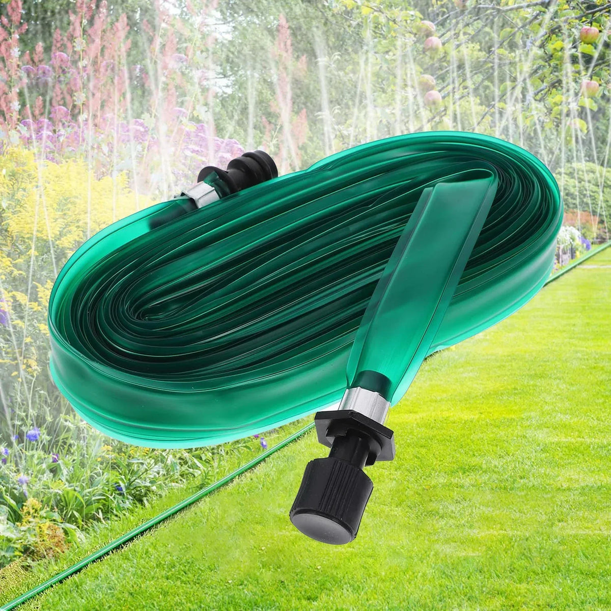 A coil of green flat soaker hose with a spray nozzle lying on a green lawn amidst garden foliage.