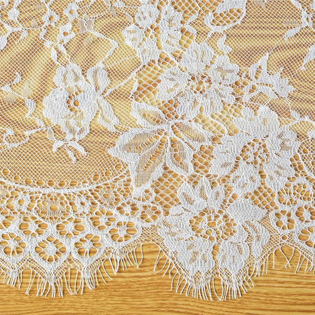 Vintage white embroidered floral lace table runner with scalloped edges on a wooden surface.