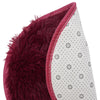 A close-up of a deep burgundy shaggy round rug with white polka dots and red trim.
