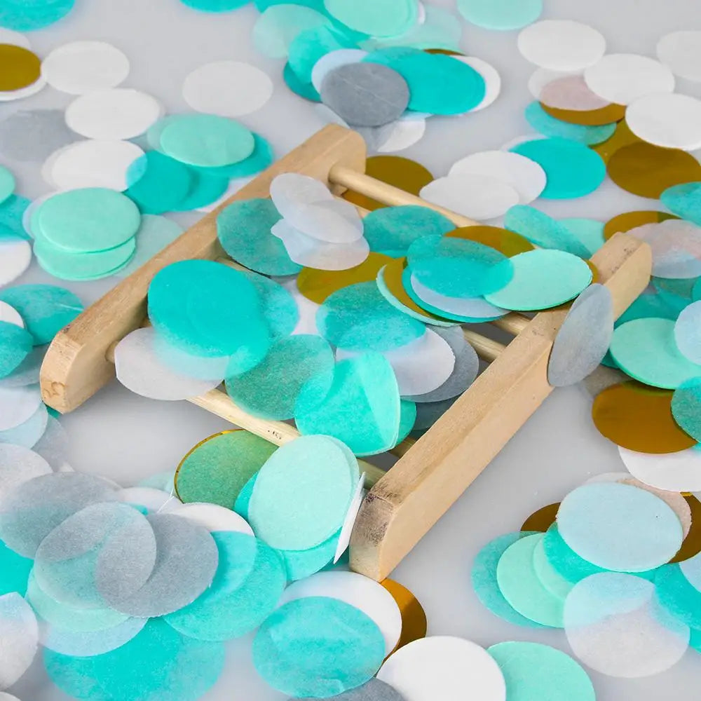 Gemischtes Farbpapier-Confetti in Türkis-, Silber- und Goldtönen auf weißem Untergrund.