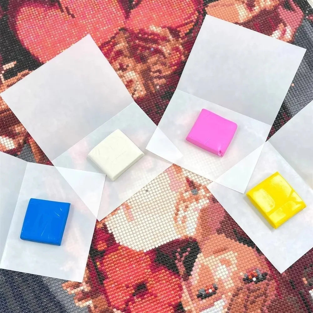 A collection of pink and yellow silicone diamond painting clay pieces are displayed on a patterned fabric.
