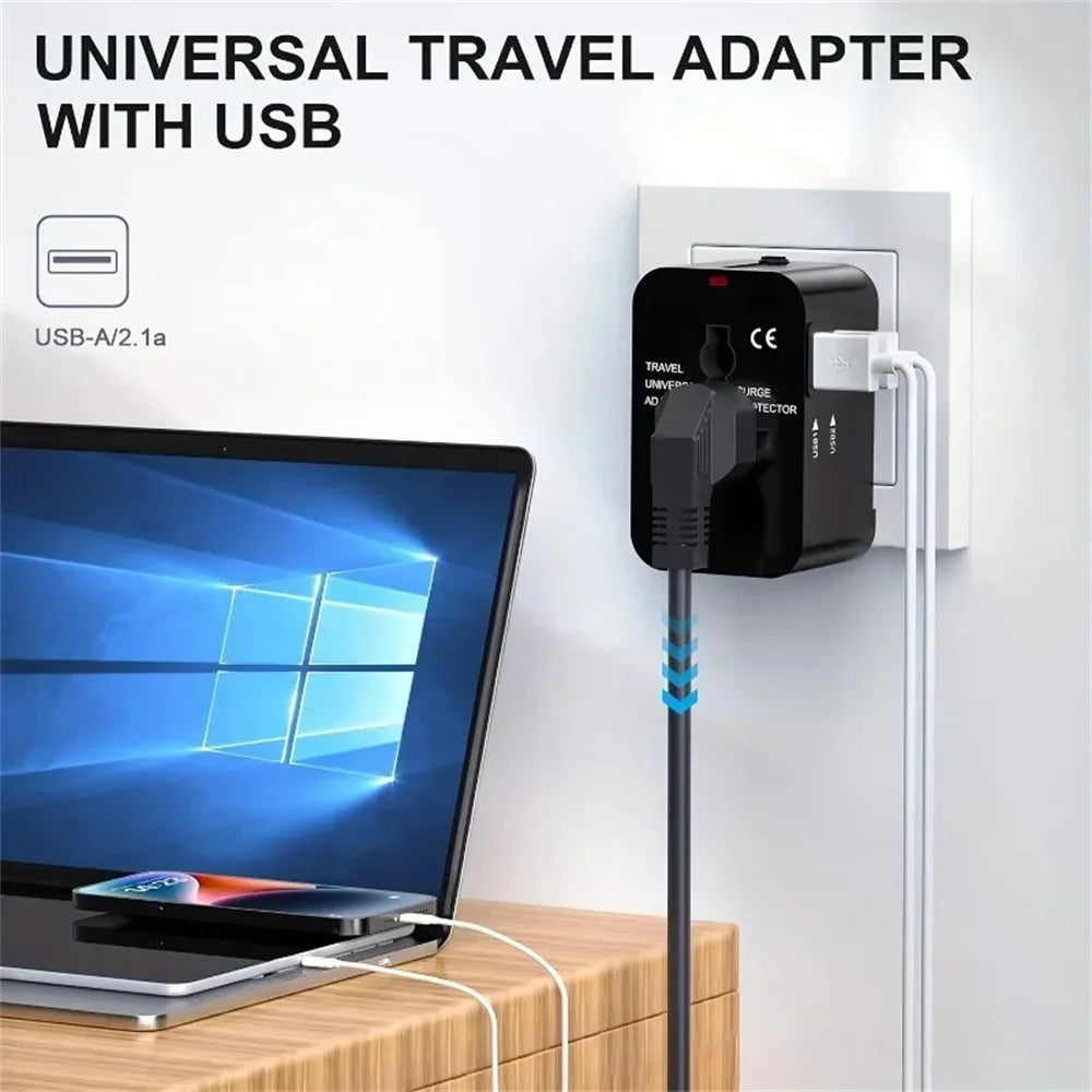 Schwarzer universeller Reiseadapter mit USB-Anschluss, eingesteckt in eine weiße Steckdose neben einem Laptop.