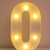 A glowing, oval-shaped LED letter night light shaped like the number zero, illuminating the surrounding area.