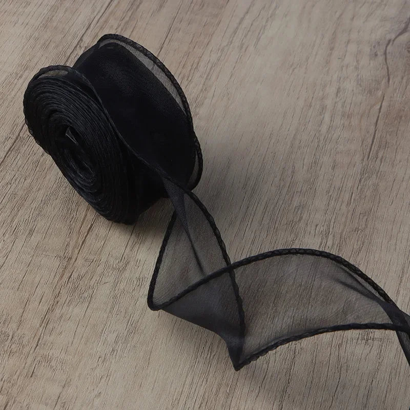 Black wavy edge organza ribbon rolled up and unwound on a wooden surface