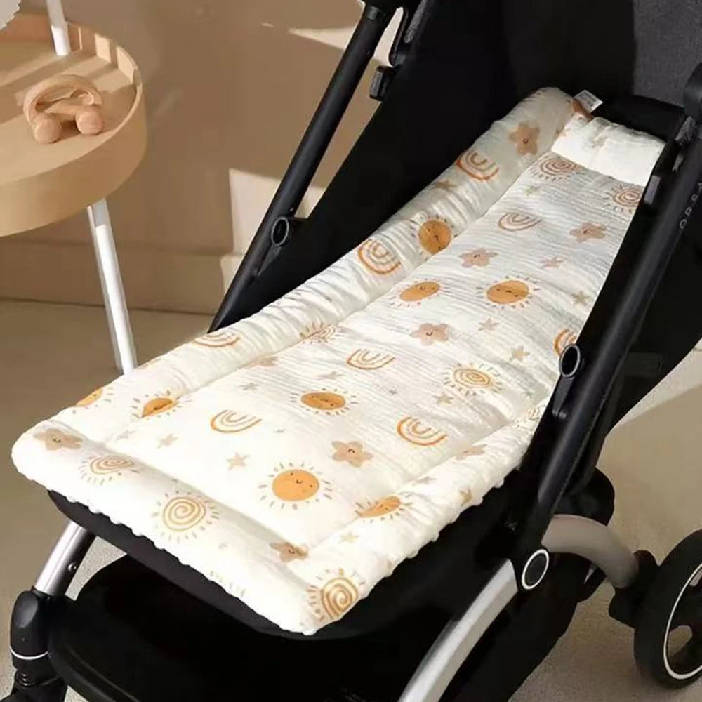 A padded white and gold patterned seat cushion is shown installed in a black baby stroller seat.