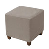 A square ottoman slipcover in a light taupe color with a textured diamond pattern.