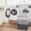 A large foldable canvas laundry basket stands in front of white washing machines in a kitchen setting.