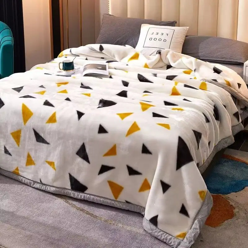 Weiße Plüschdecke mit schwarz-gelbem geometrischem Muster über einem Bett drapiert.