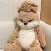 A fluffy brown rabbit plush toy with white accents sitting on a light-colored sofa.