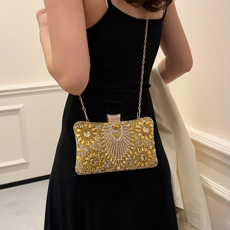 A woman holds a rectangular gold rhinestone evening clutch with a chain strap against a black dress.