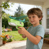 A boy holds a green foam catapult airplane toy with a teal wing, outdoors.