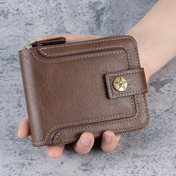 A brown leather zip-around bi-fold wallet is held in a hand against a gray background.