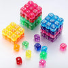 A collection of colorful acrylic D6 dice in various shades of red, green, blue, and yellow are displayed on a white surface.