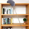Extendable microfiber duster with an adjustable handle displayed on a wooden shelf.