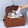 A brown leather toiletry bag is open, displaying various cosmetic and skincare products, with a hand reaching toward the cont