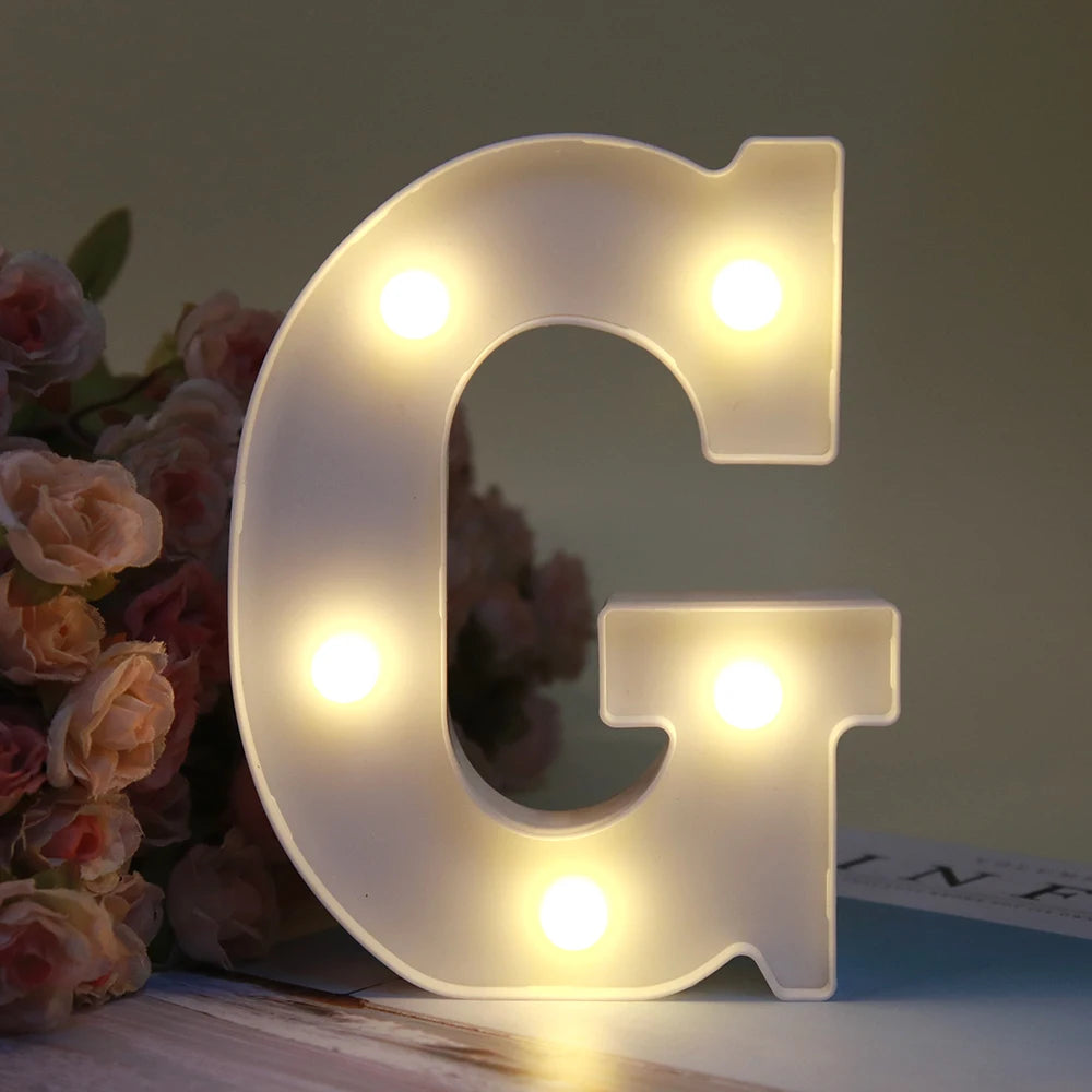 Lumière de nuit en forme de lettre G, alphabet blanc lumineux LED, posée sur une surface en bois.