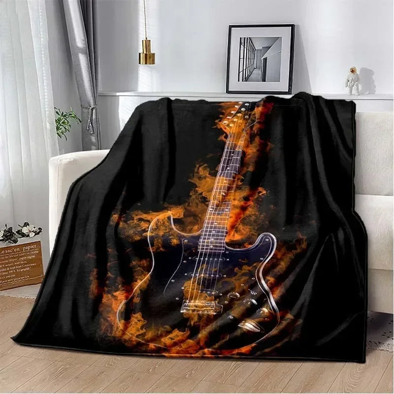 A black flannel throw blanket featuring a graphic design of an electric guitar engulfed in orange flames.