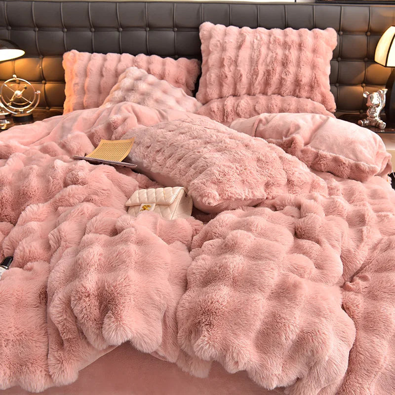A pink faux fur bedding set featuring a duvet, pillows, and a matching blanket displayed on a bed.