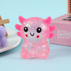 A pink, glittery axolotl squishy stress ball with air vent resting on a light blue surface.