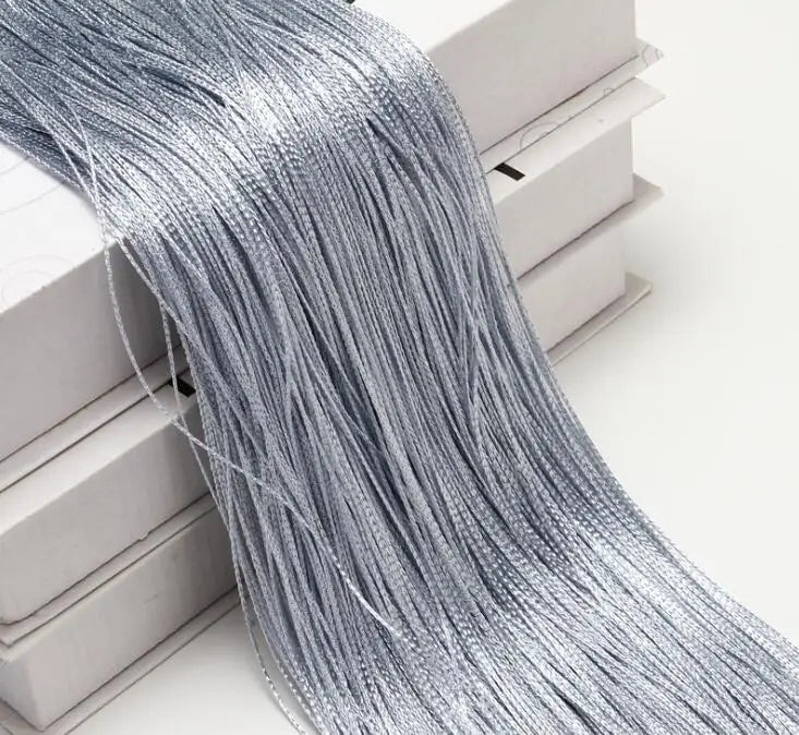 Silver beaded thread curtain hanging, showing the long strands draped over white boxes.