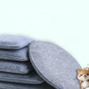 A stack of gray needle felting mats for wool crafting with a small dog toy resting on top.